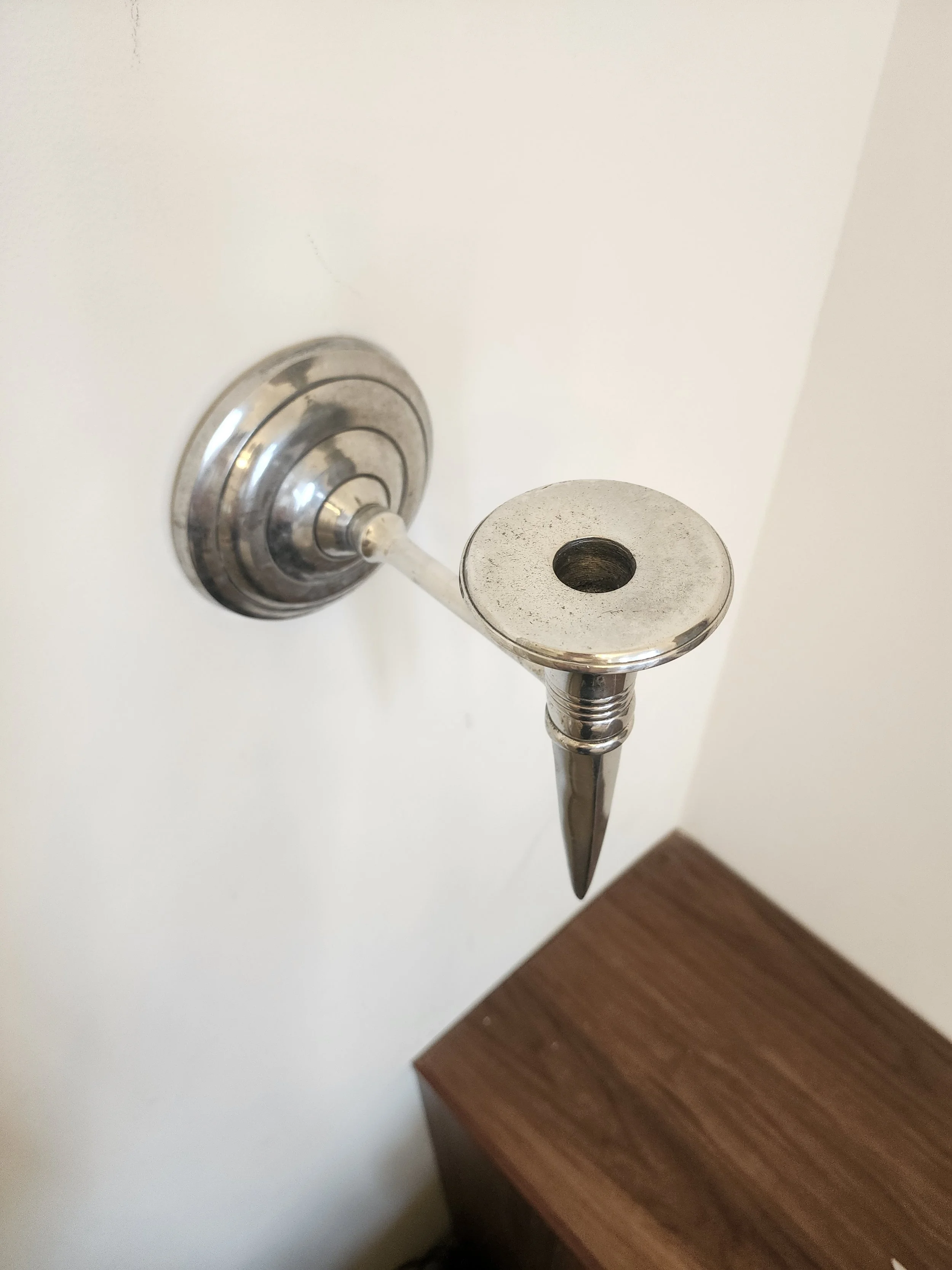 Close-up of candle cup and polished chrome surface with light patina.