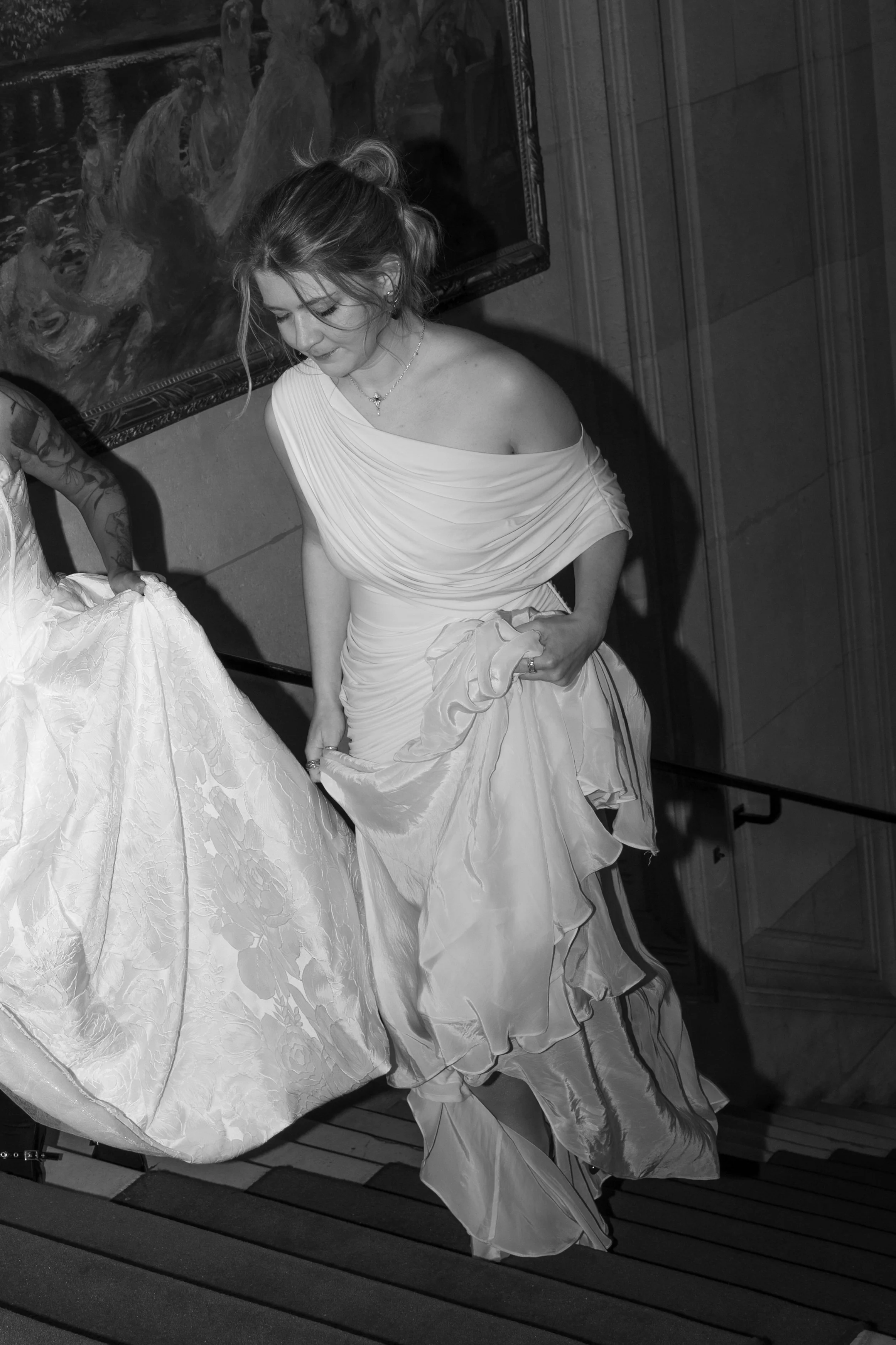 Jeune femme portant une robe de bal élégante, se tenant dans une galerie ou un musée, avec un tableau classique en arrière-plan.