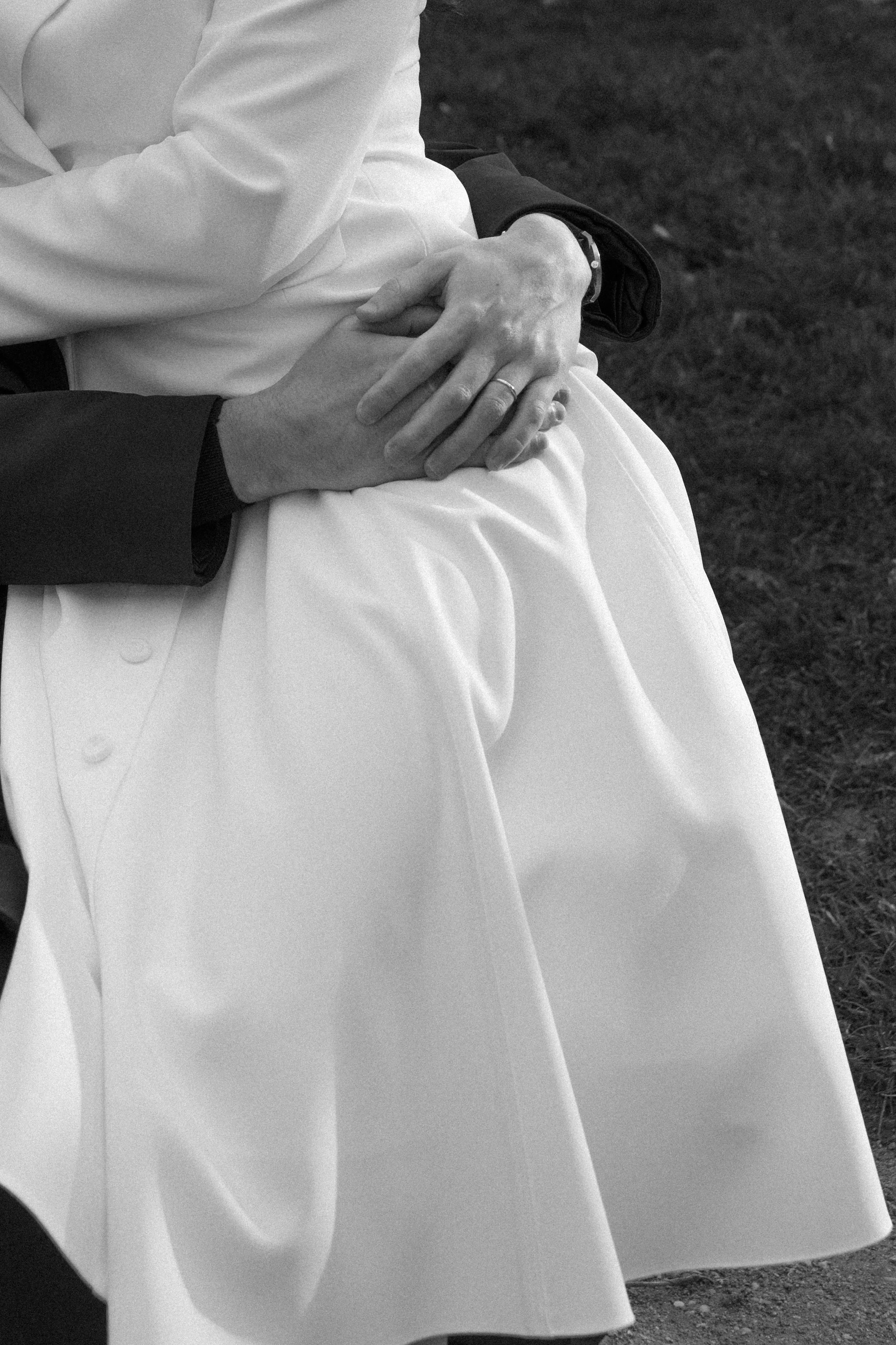 Deux personnes qui portent des vêtements formels, assises l'une à côté de l'autre, tenant leurs mains ensemble, avec un fond en herbe.
