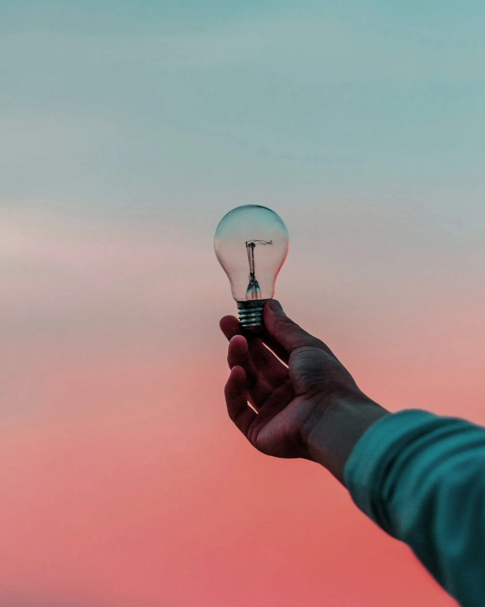 Innovation and brand strategy represented by person holding a lightbulb during sunset, corporate consulting imagery Perth WA