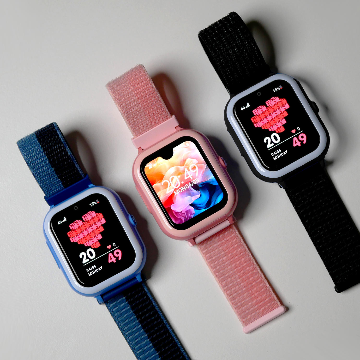 Three smartwatches with colored bands lying on a white surface, displaying digital heart shapes and dates on their screens.