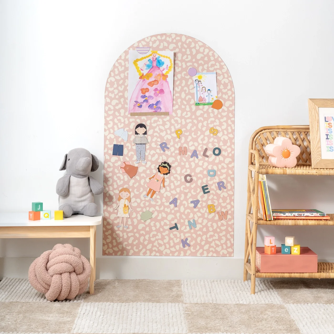 Children's room decorated with children's artwork, stuffed animals, foam blocks, and a wicker bookshelf.