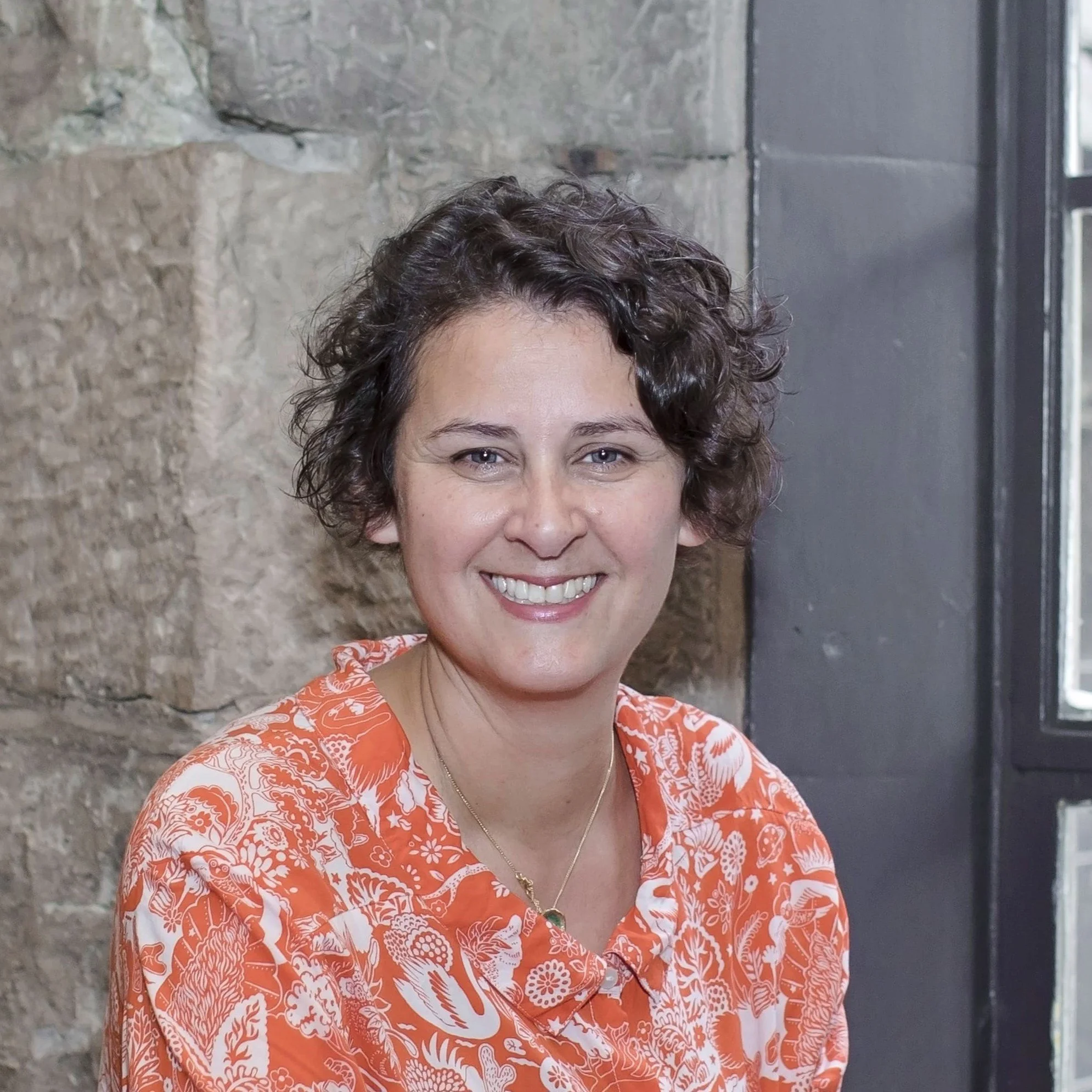 Portrait photograph of author Emma Dhesi against a wall