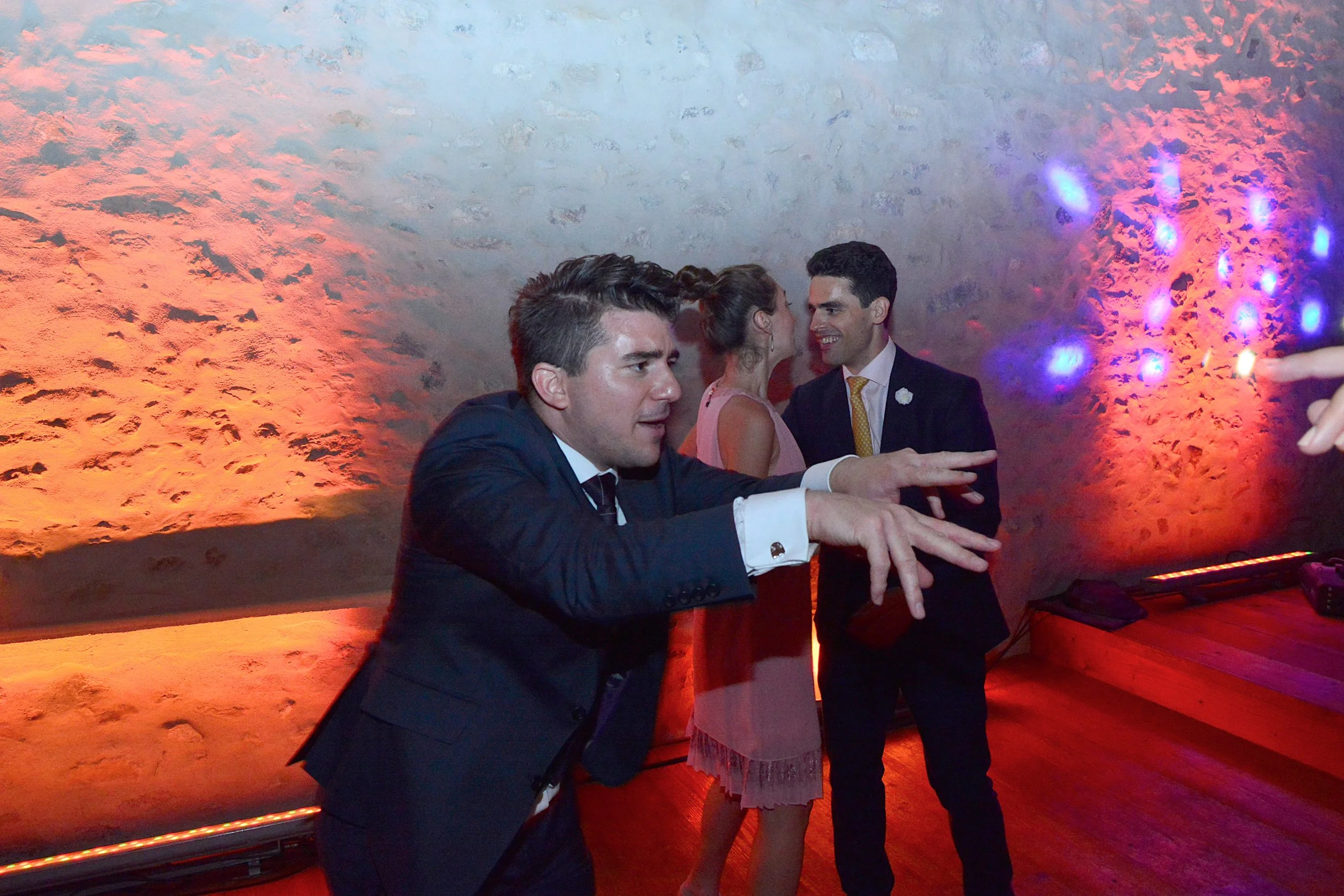 Groupe de personnes dansant et s'amusant lors d'une fête ou d'un événement social, avec des lumières colorées.