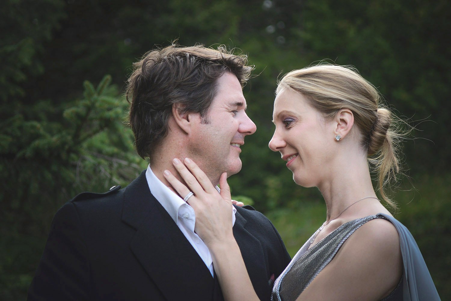 Un couple en plein front à front, semblant s'aimer, en extérieur avec des arbres en arrière-plan.