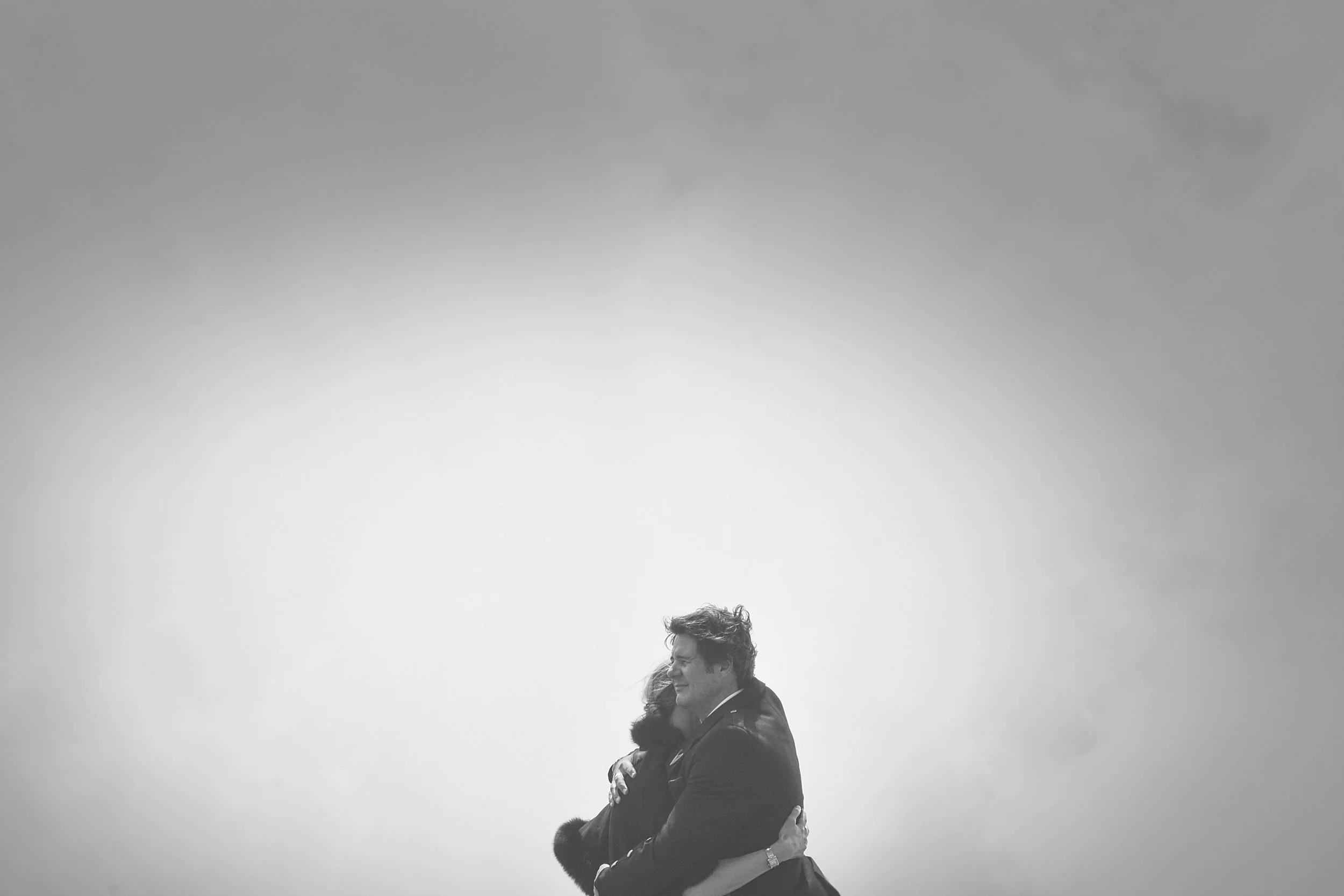 Deux personnes s'étreignent dans un ciel nuageux.