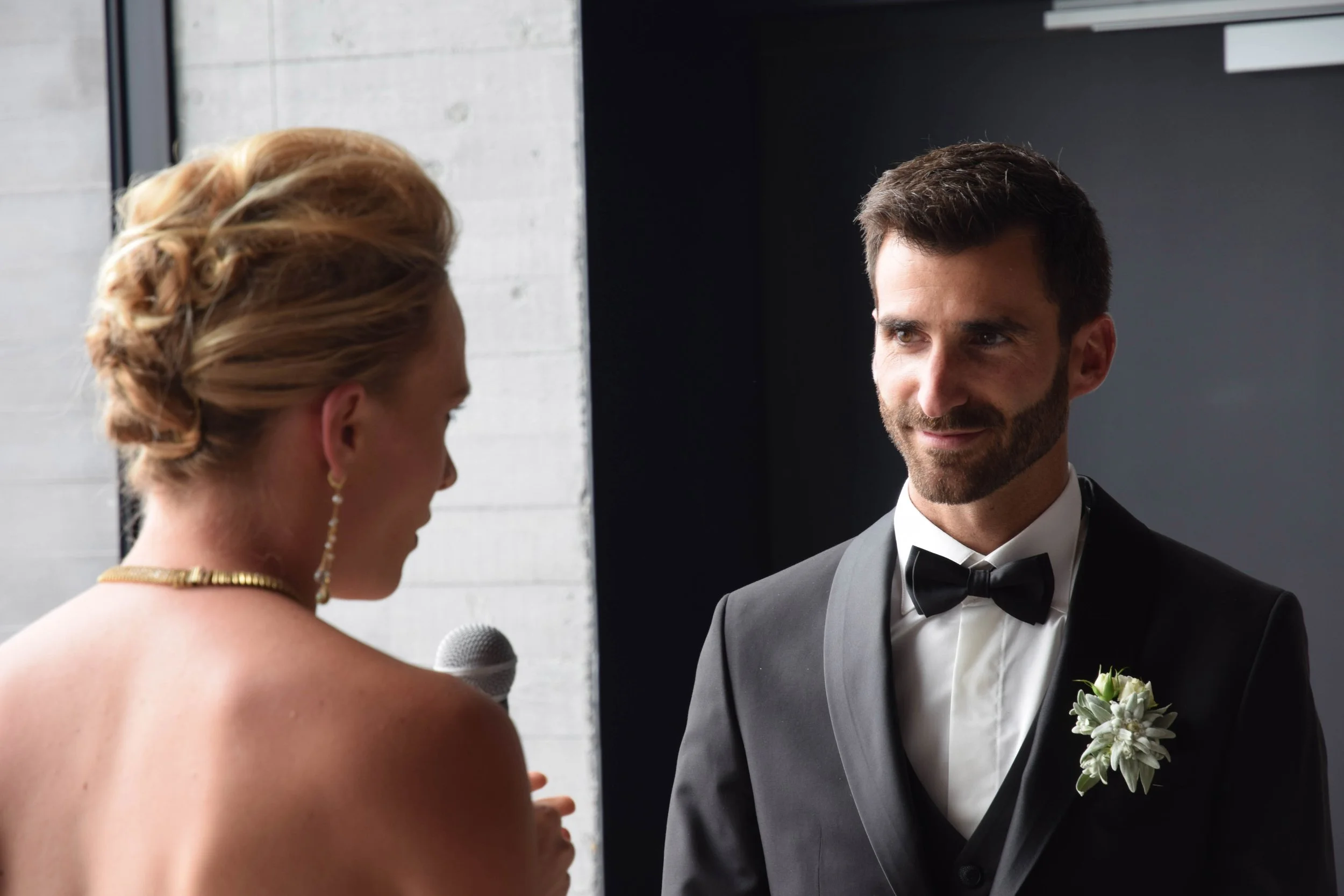 Un homme en costume de mariage et une femme avec un microphone lors d'une cérémonie.