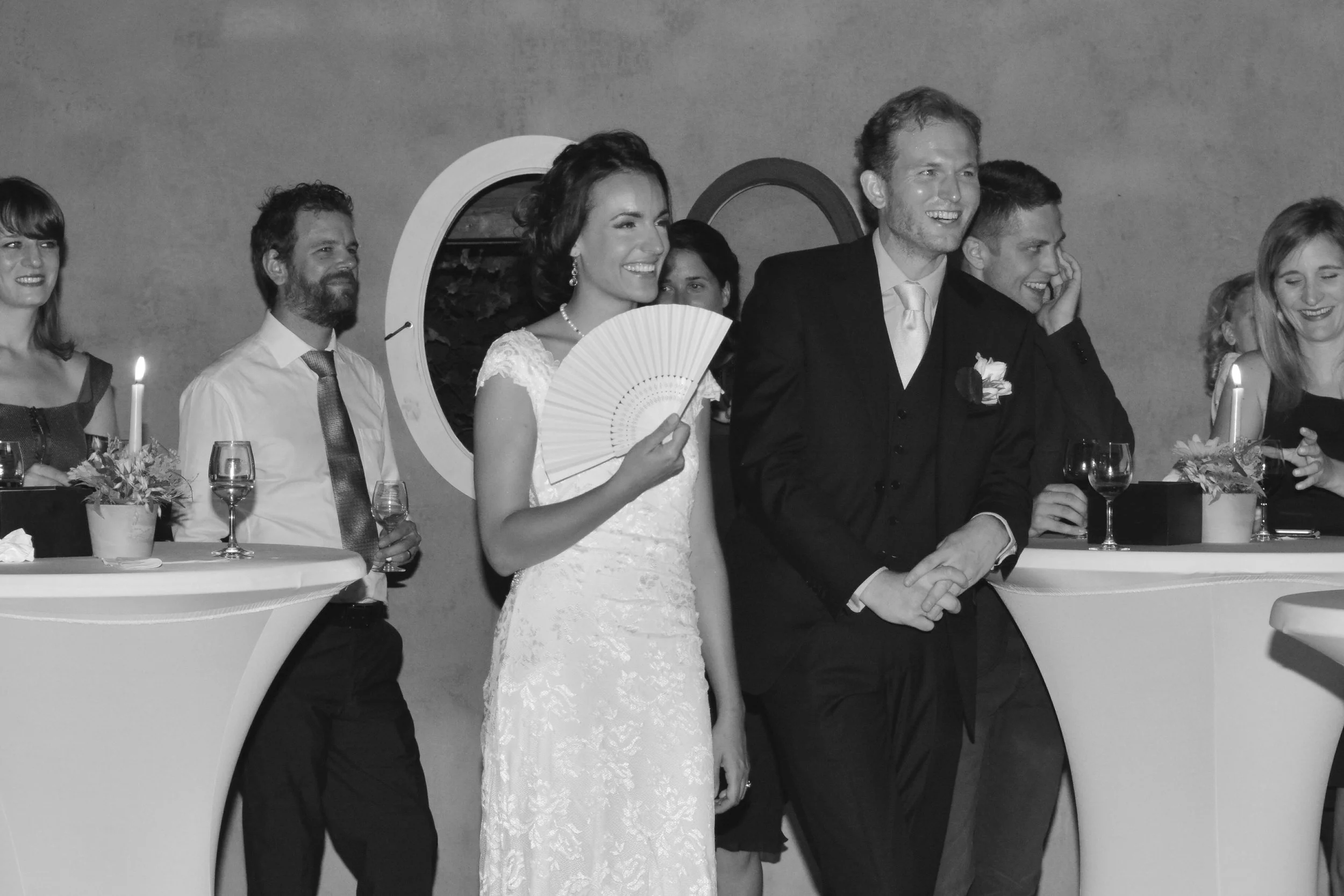 Groupe de personnes lors d'un mariage, souriantes et habillées formellement, avec une femme portant un éventail.
