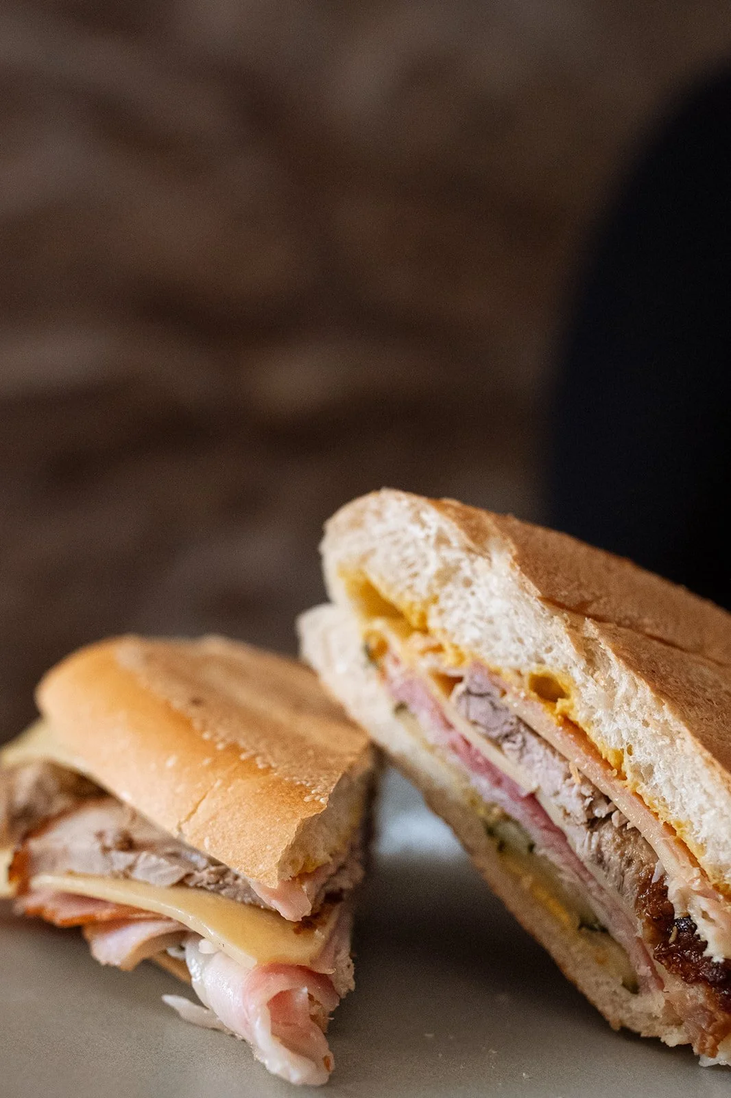 Close-up of a sandwich cut in half, showing turkey, ham, cheese, and bread.