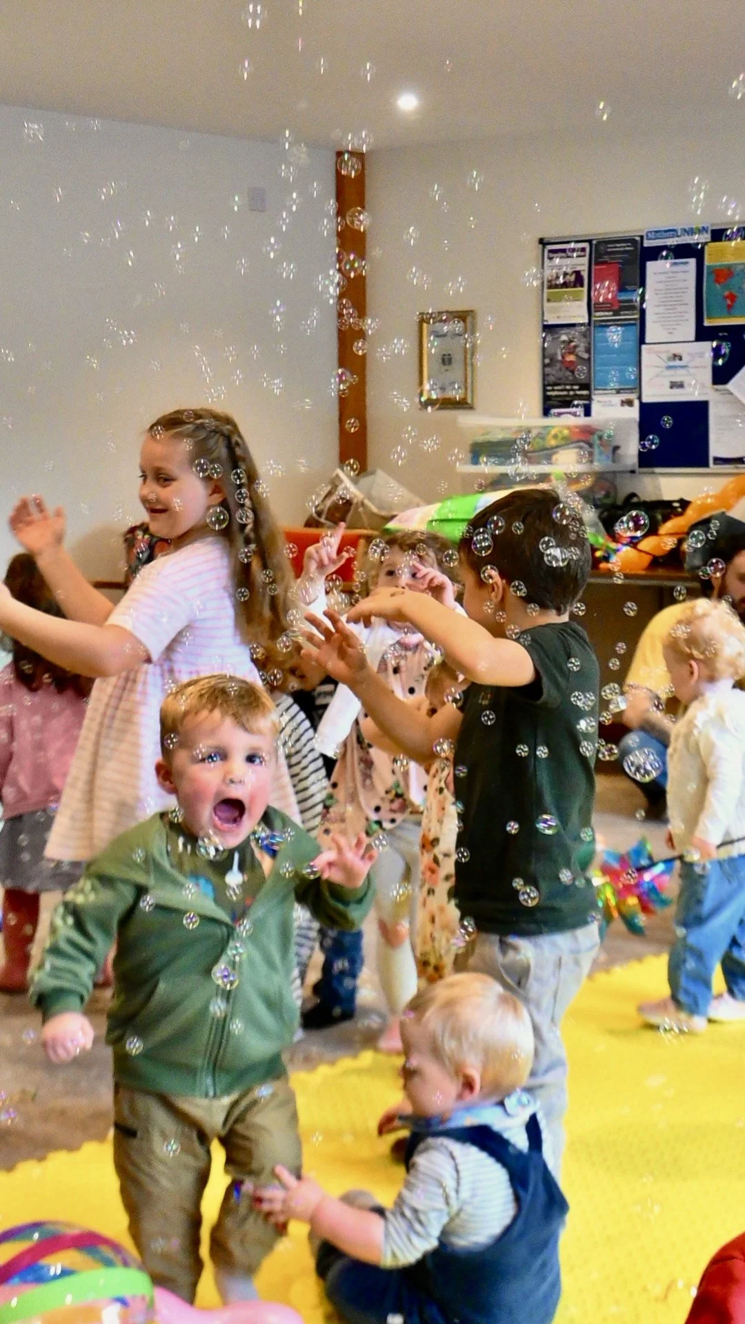 toddler and pre-school age boys and girls smiling and laughing among floating bubbles