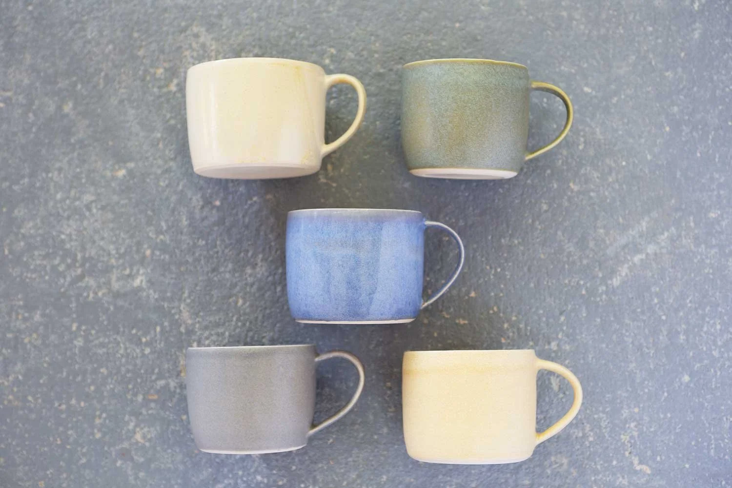 Five ceramic coffee mugs painted in a harmonious range of glaze colours developed by Claire.