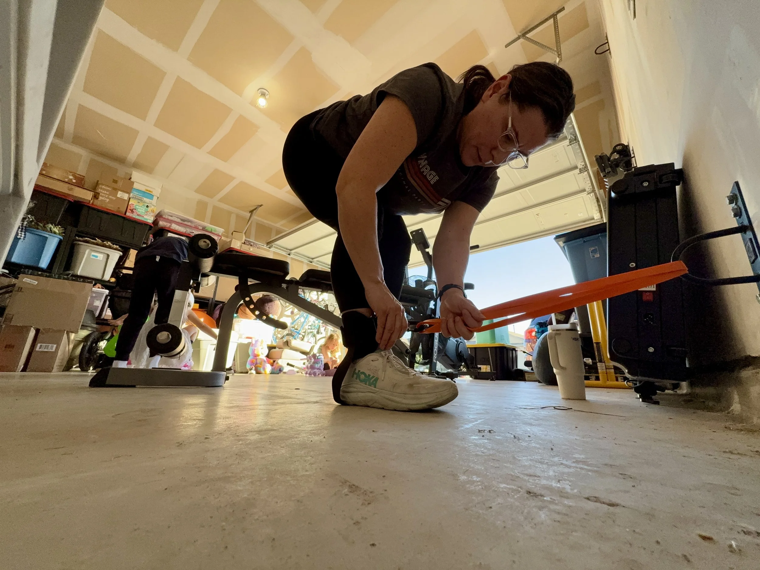 a mom working out in her garage gym using resistance bands to build muscle.