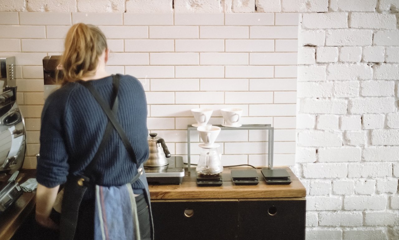 A barista pouring coffee in a local shop to represent human centric branding that supports independent businesses