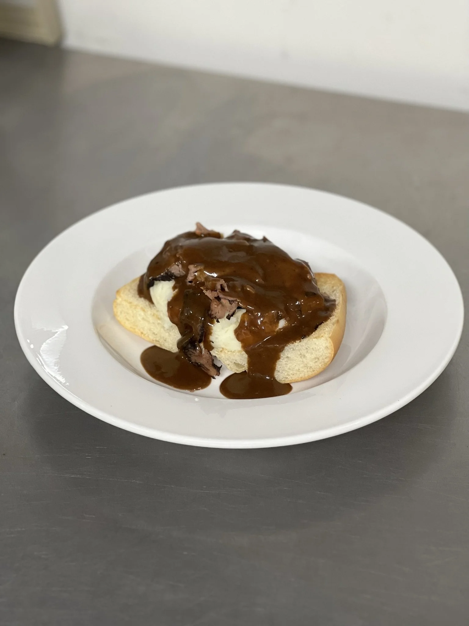 Elm Creek Beef An open sandwich with meat, cheese, and brown gravy on a white plate.