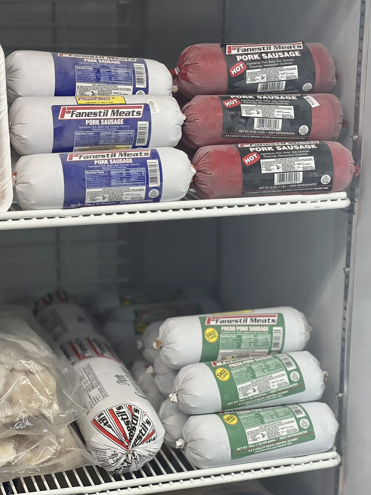 Elm Creek Beef Frozen pork sausage packages on supermarket shelves, including original, hot, and fresh varieties.