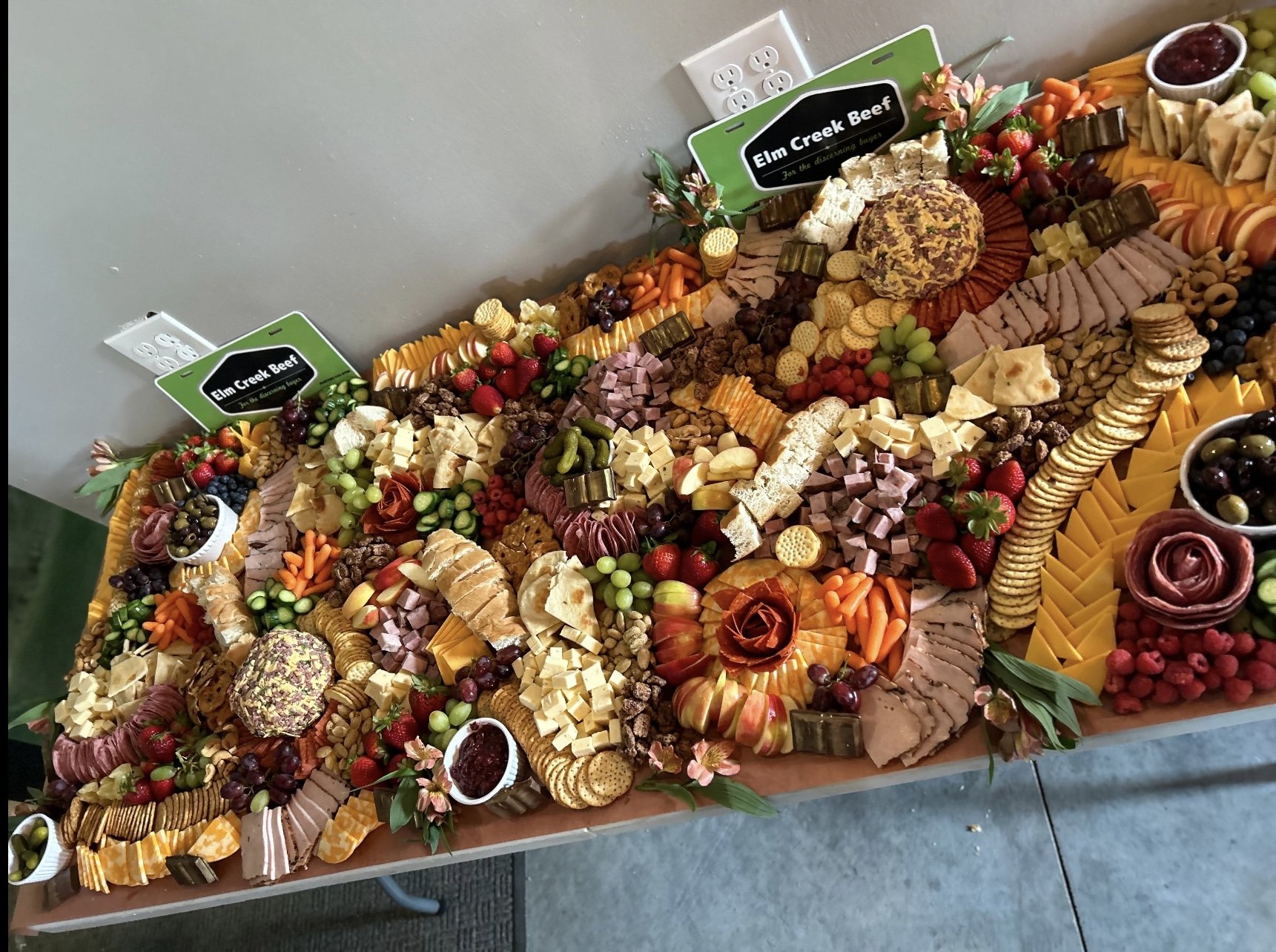 Elm Creek Beef Large charcuterie board with cheeses, meats, crackers, fruits, and appetizers, labeled "Elm Creek Beef".