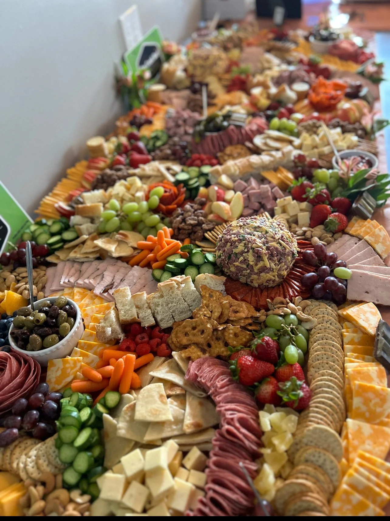Elm Creek Beef A large, colorful party platter with a variety of cheeses, sliced meats, fruits, vegetables, crackers, and dips arranged on a table.