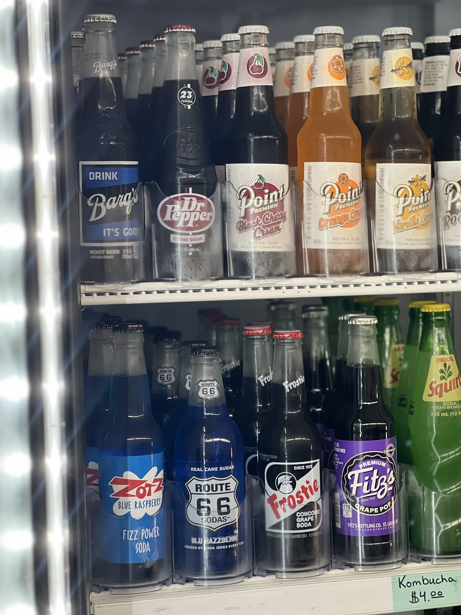 Elm Creek Beef A vending machine shelf stocked with various soda bottles and cans, including Root Beer, Dr. Pepper, Black Cherry Cream, Orange Cream, Vanilla Cream, Blue Raspberry, Route 66, Frostie, and Fit3 Grape Pop.