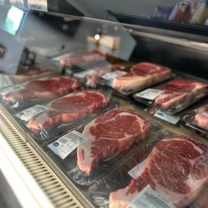 Elm Creek Beef Packages of raw beef steaks in a refrigerated display case.