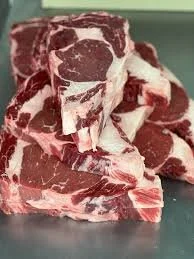 Elm Creek Beef Several cuts of raw beef meat stacked on a surface.