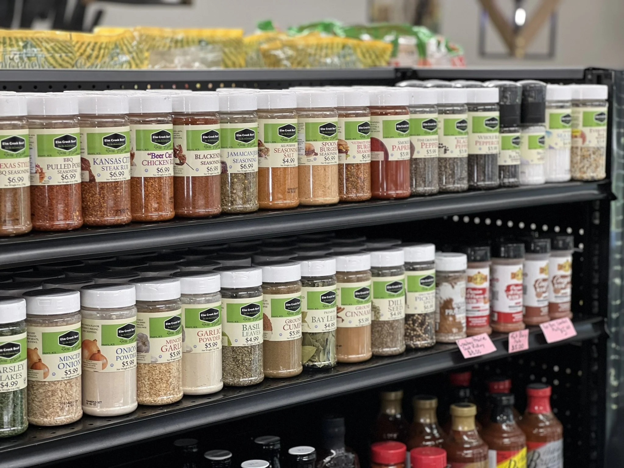 Elm Creek Beef Shelves stocked with various seasonings and spices in jars and bottles at a store.