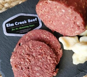 Sliced Elm Creek Beef sausage links with white cauliflower on a black plate.