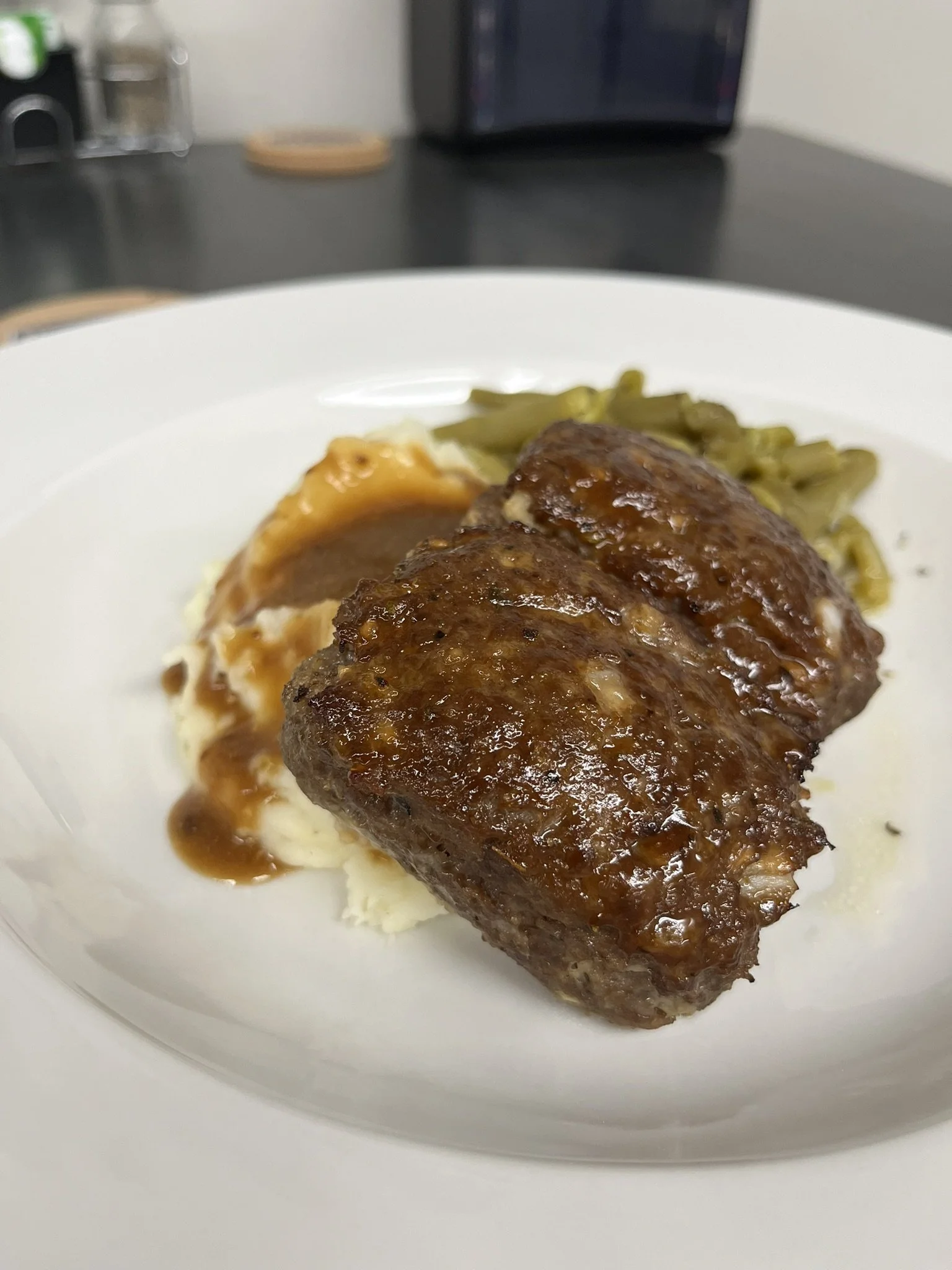 Elm Creek Beef Plate of meatloaf with gravy, mashed potatoes with gravy, and green beans.