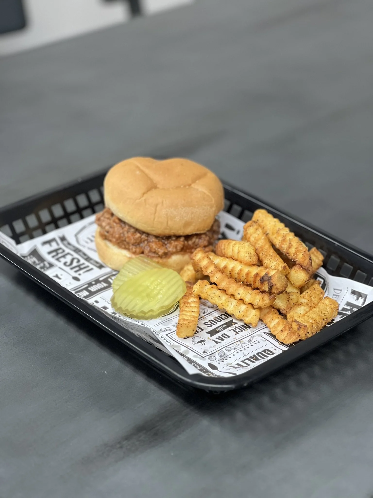 Elm Creek Beef Tray with a cheeseburger slider, crinkle-cut fries seasoned with spices, and a pickle spear.