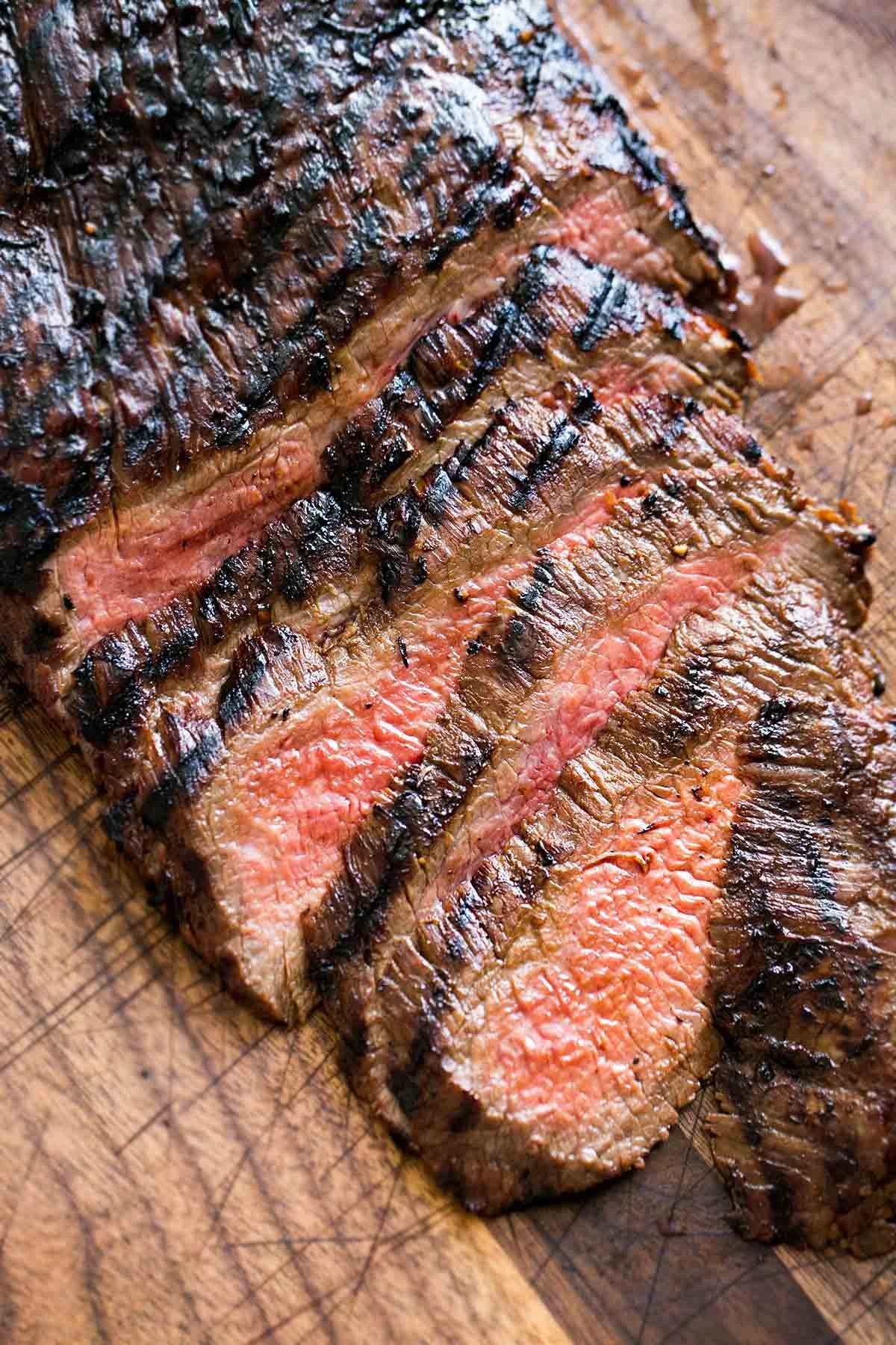 Elm Creek Beef Sliced grilled steak with sear marks on a wooden cutting board.