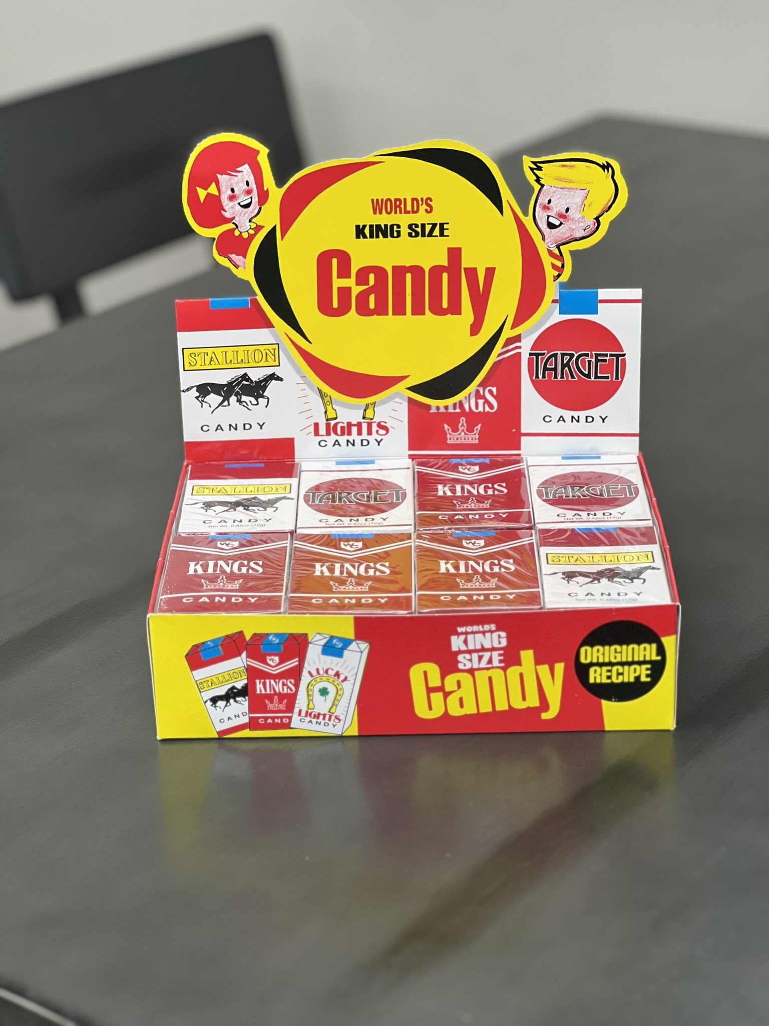 Elm Creek Beef A colorful display box of large-sized candy packs with vintage-style packaging, featuring brands like Stallion, Target, Kings, and Lights, set on a gray table.