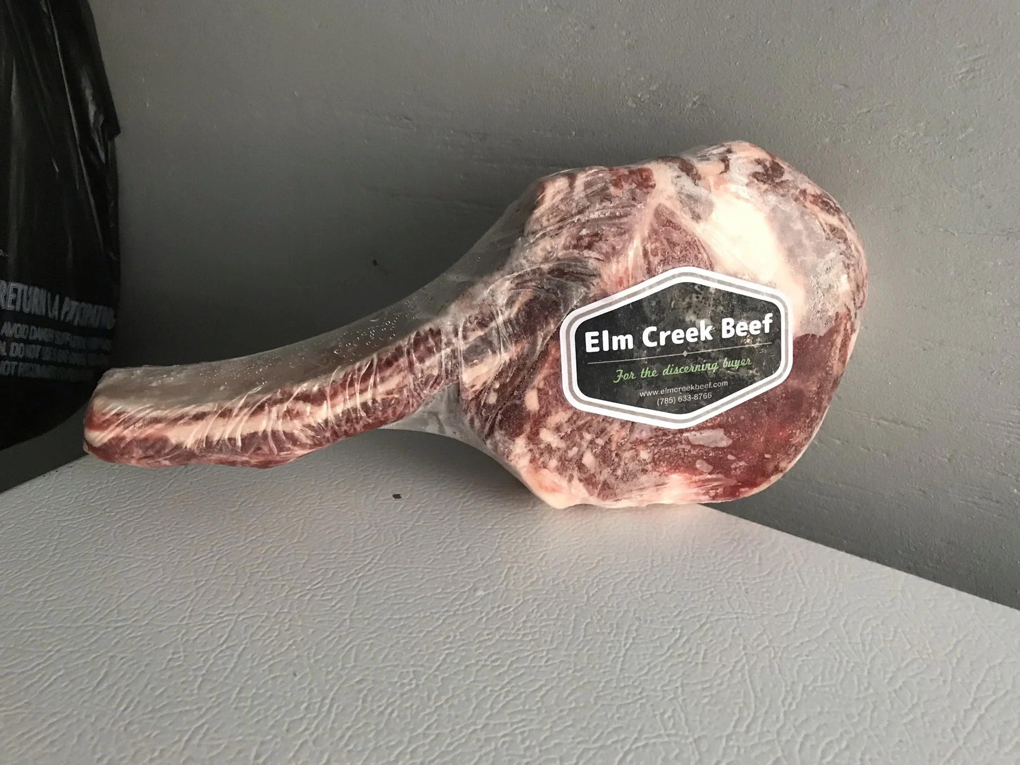 Elm Creek Beef A vacuum-sealed piece of beef labeled Elm Creek Beef on a white surface against a gray wall.
