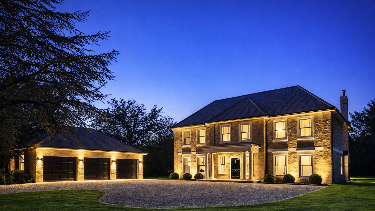Elegant two-story brick house with illuminated windows and a three-car garage, surrounded by a manicured lawn and trees, during twilight.