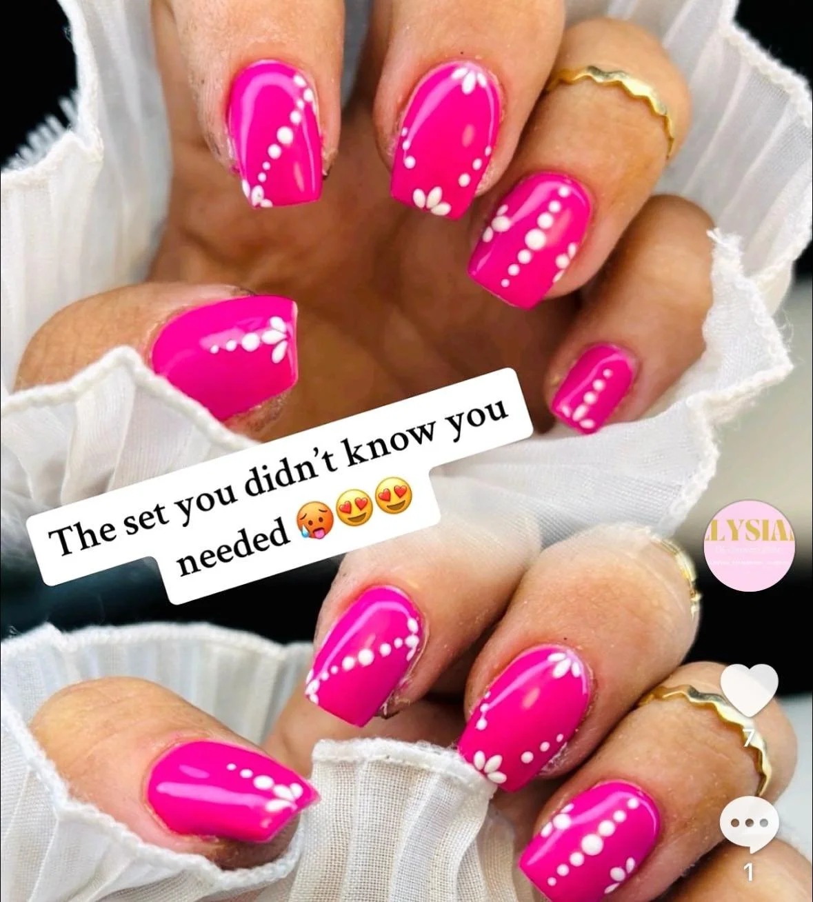 Close-up of hands with pink nail polish and white floral and dotted nail art designs, showing rings and a white cloth sleeve. Text overlay reads, 'The set you didn't know you needed' with emojis.