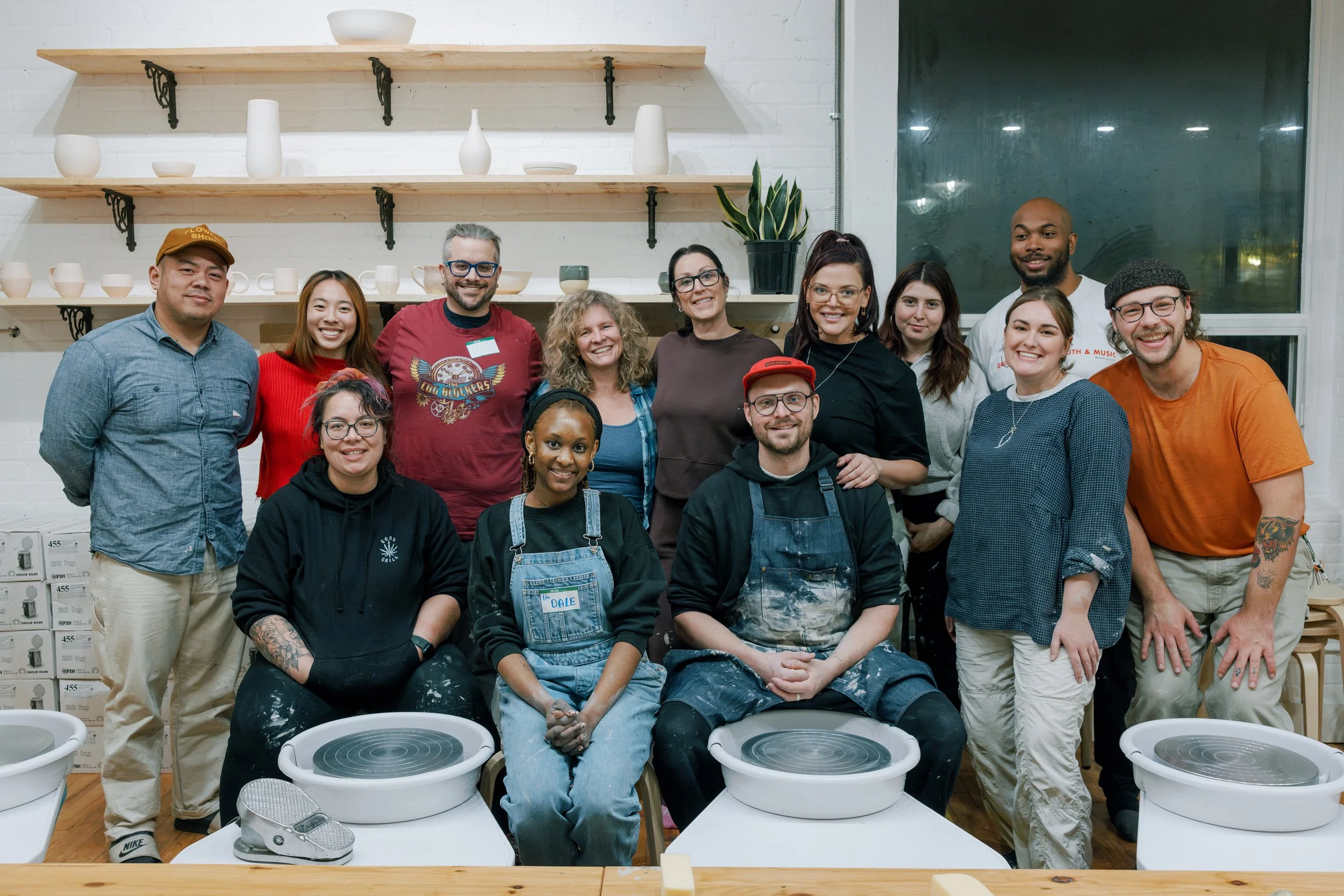 Group of people in a Studio Ceramica, a pottery studio in Toronto, some with pottery wheels, smiling at the camera.