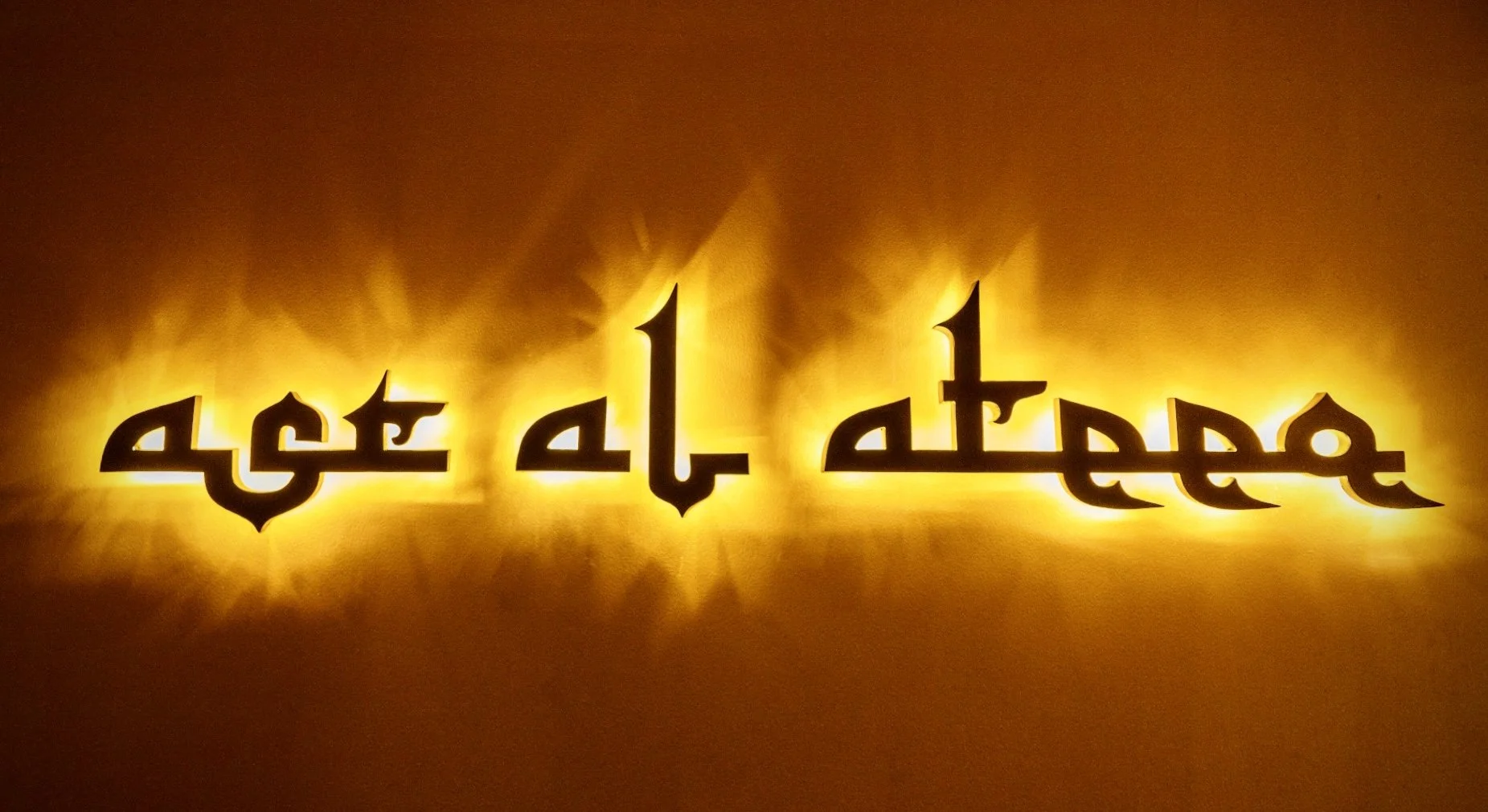 Illuminated Arabic-styled calligraphy on a yellow background.