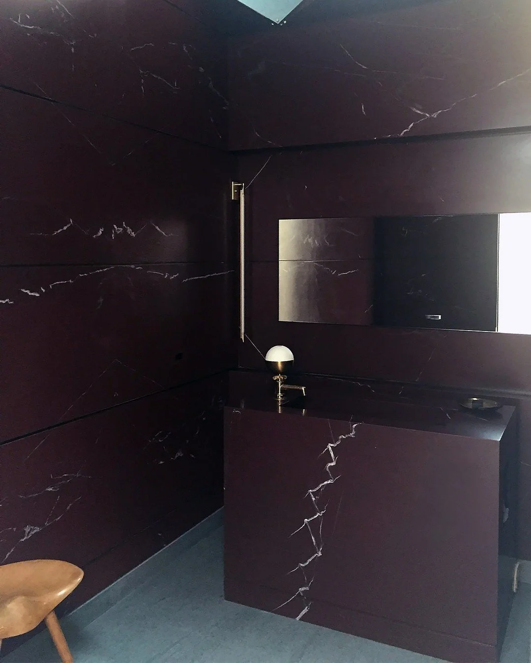 West Hollywood Bathroom | Custom Stonework
Rich, deep maroon stone defines this bespoke space&mdash;every surface, from the wall panels to the vanity and integrated sink, is custom fabricated from a single natural stone. The seamless flow of veining 