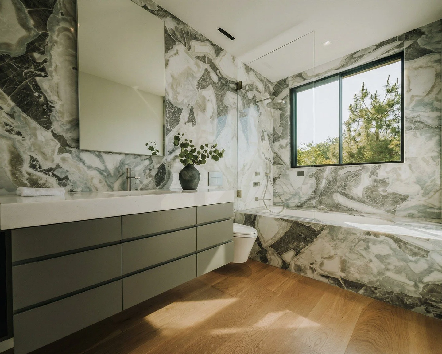 When the stone does the talking, everything else steps aside.
This Bel Air bath was conceived around a single material &mdash; an intensely figured marble selected slab by slab for continuity across walls, shower, and tub surround. The veining maps l
