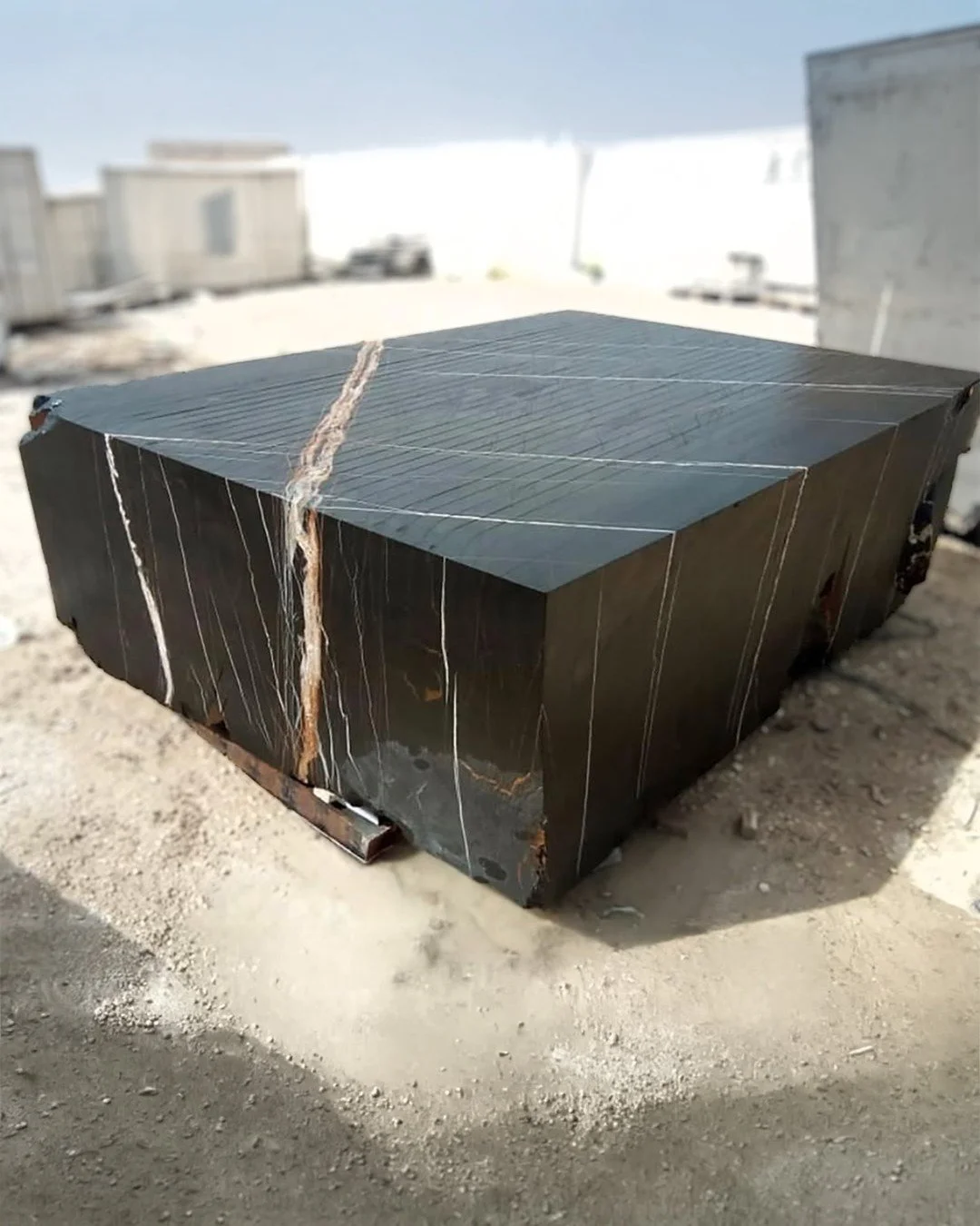 Before the slab. Before the cut. Before the decision.

This is a block of Sahara Noir &mdash; jet black with white and gold veining running through it like lightning. At this stage it could become anything. A statement dining table. A freestanding tu