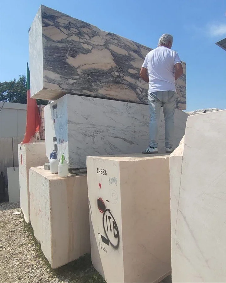 You wet the stone to see it tell the truth.

A dry block hides everything &mdash; the depth, the movement, the color shifts that will define a room. So you climb, you spray, you photograph, you move to the next one. This is how the right slab gets fo