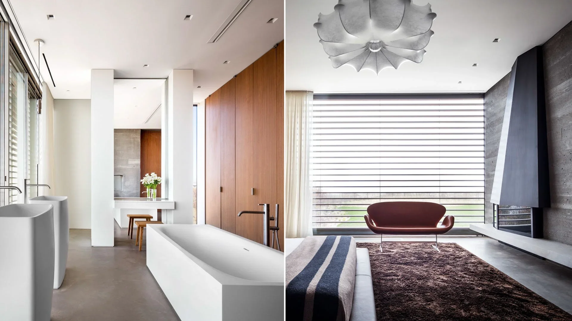 Interior of a modern home featuring a bathroom with a white bathtub, sinks, and stools on the left, and a living room with a red sofa, striped blanket, and large window with blinds on the right.