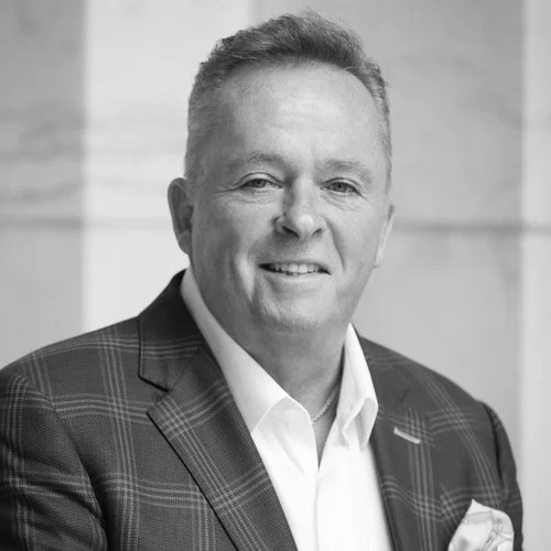 Black and white portrait of a smiling man in a suit and tie.