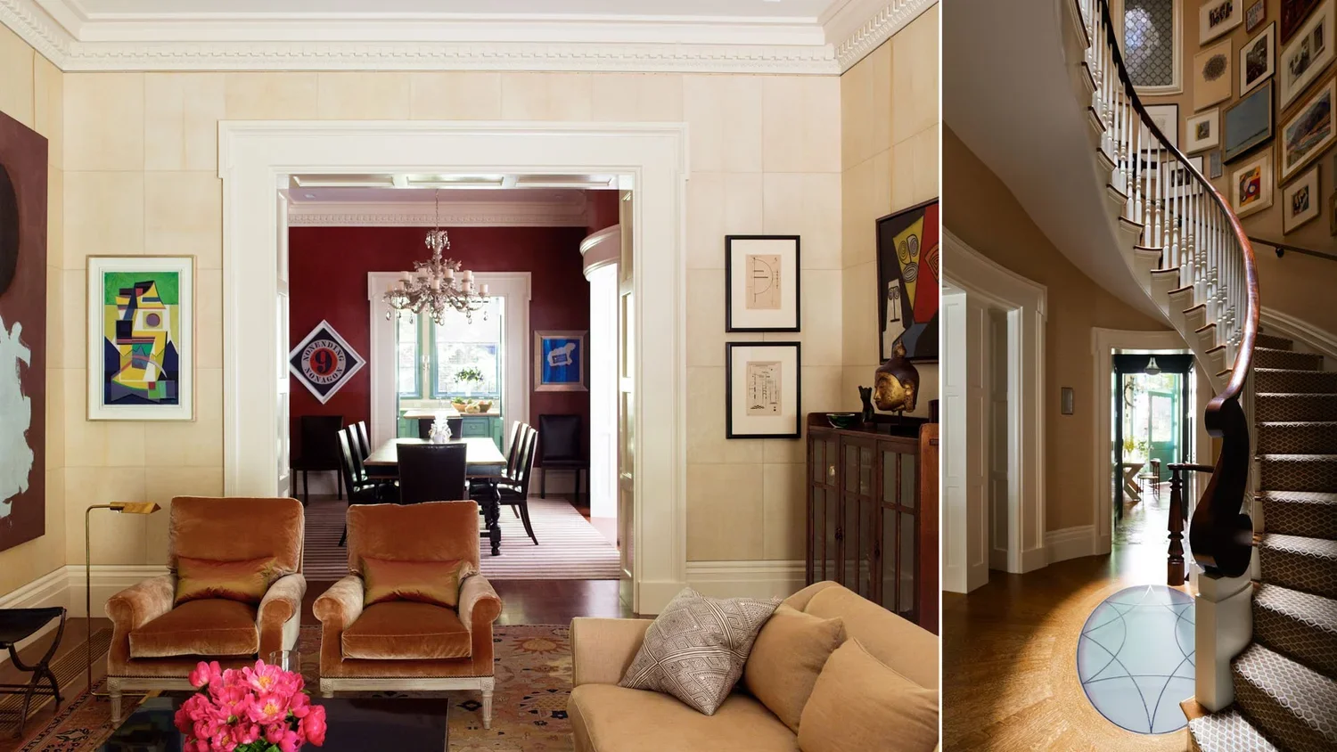 A spacious living room with beige walls and a beige sofa with patterned pillows, two rust-colored armchairs, a coffee table with pink flowers, and artwork on the walls. An open doorway leads to a dining area with a chandelier and a window. Adjacent i