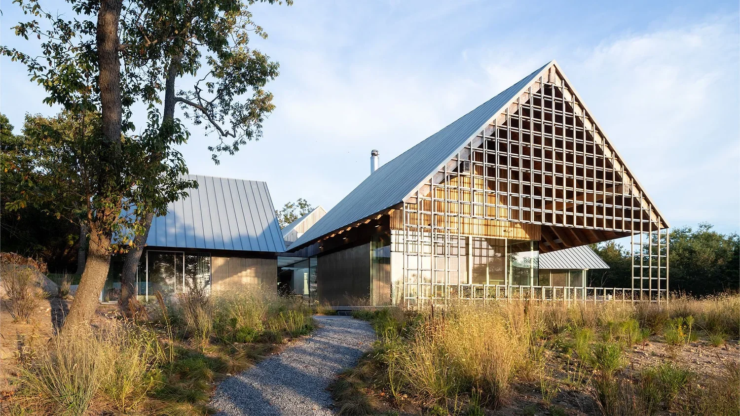 Modern house with a steeply pitched roof and large glass windows, surrounded by natural landscape.