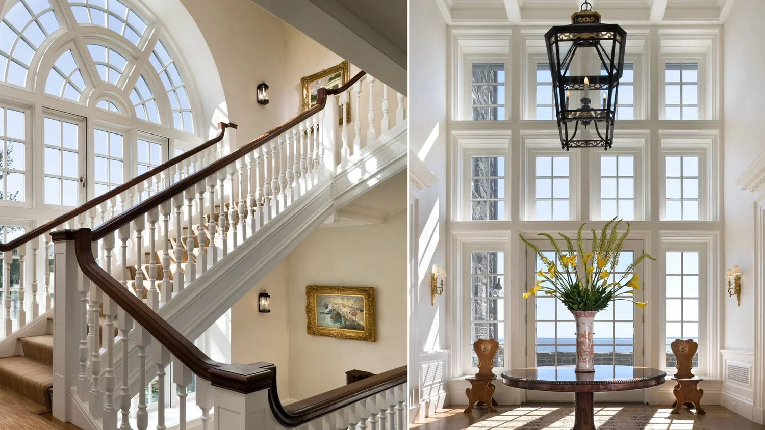 Interior of a house with large windows, a staircase with wooden handrails, a framed painting, a glass lantern hanging from the ceiling, a round table with a flower vase, and chairs, filled with sunlight.