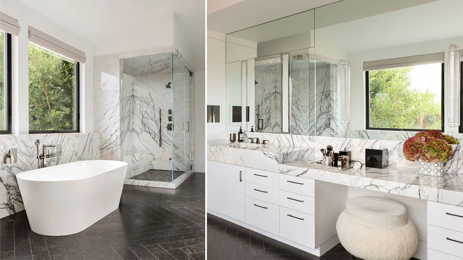 Modern bathroom with white marble surfaces, a freestanding bathtub, and a glass-enclosed shower. Large windows with greenery outside. Bathroom vanity with mirror, toiletries, a flower arrangement, and a beige stool.