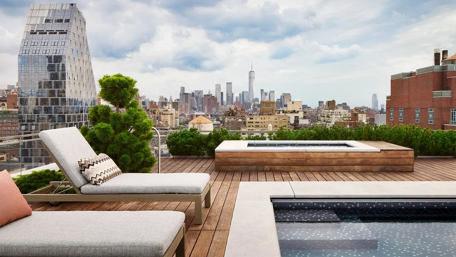Rooftop terrace with lounge chairs, potted plants, a hot tub, and a city skyline featuring One World Trade Center in New York City.