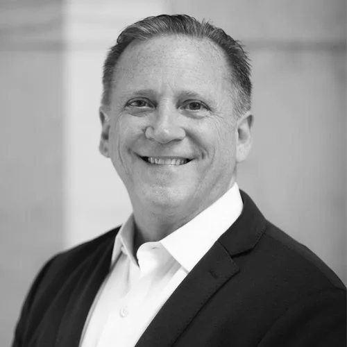 Black and white portrait of a smiling man wearing a suit and tie.