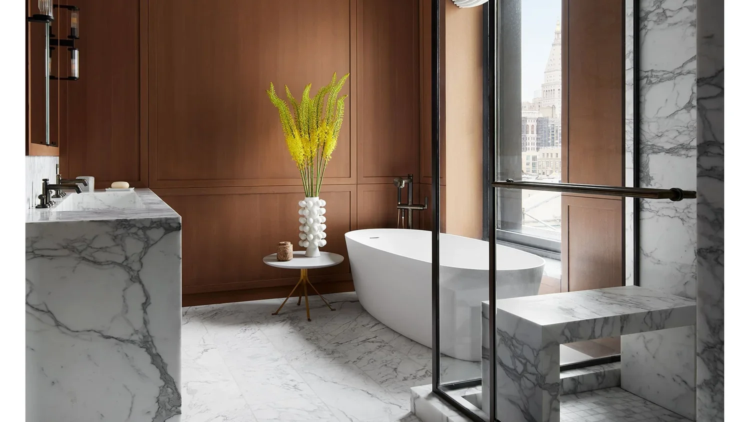 Modern bathroom with white freestanding bathtub, marble flooring, wooden wall paneling, a marble sink countertop, and a large window with a city view.