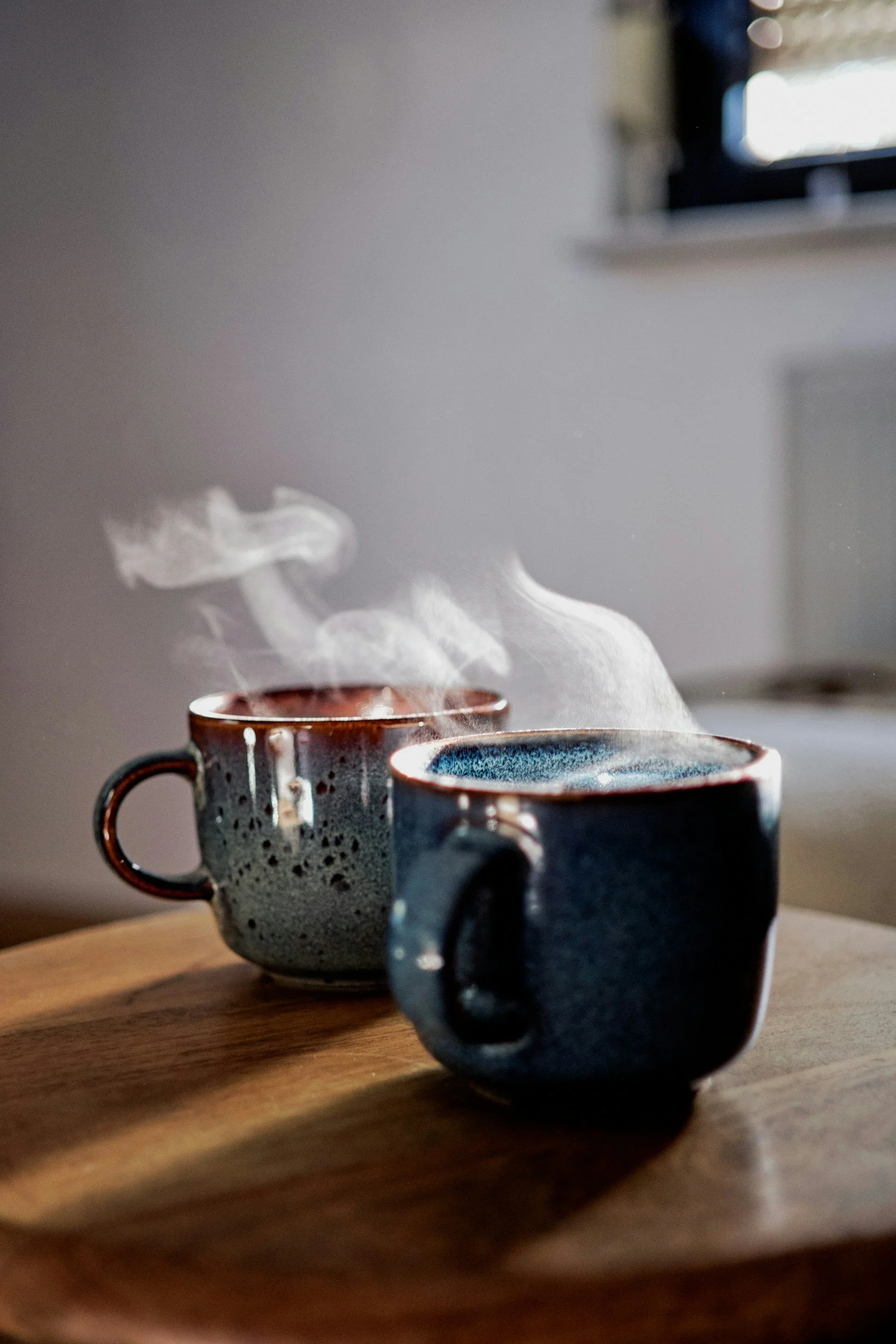 Zwei dampfende Kaffeetassen auf einem Holztisch