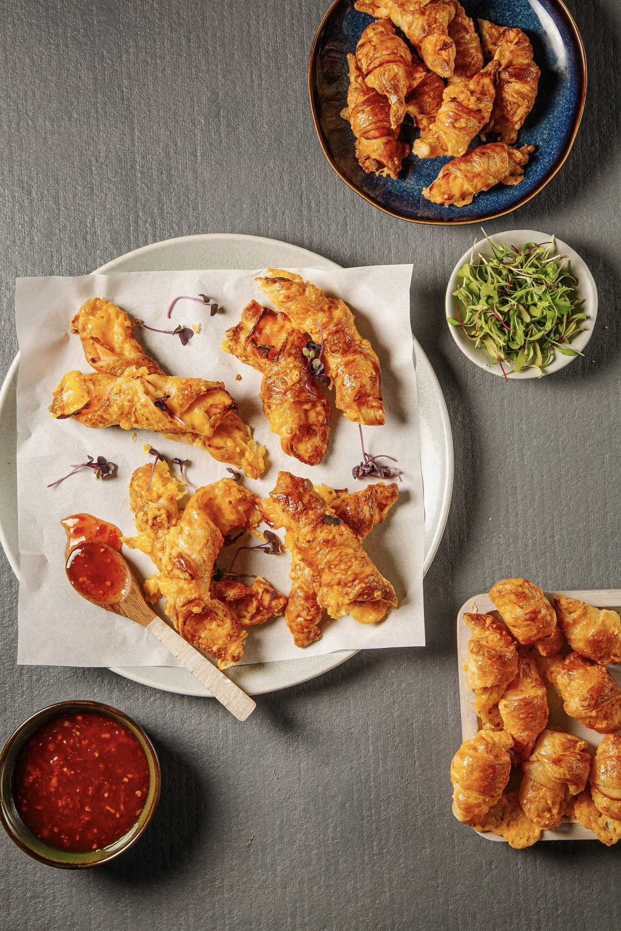 Plate of fried chicken wings garnished with microgreens, served with dipping sauces on a gray surface.